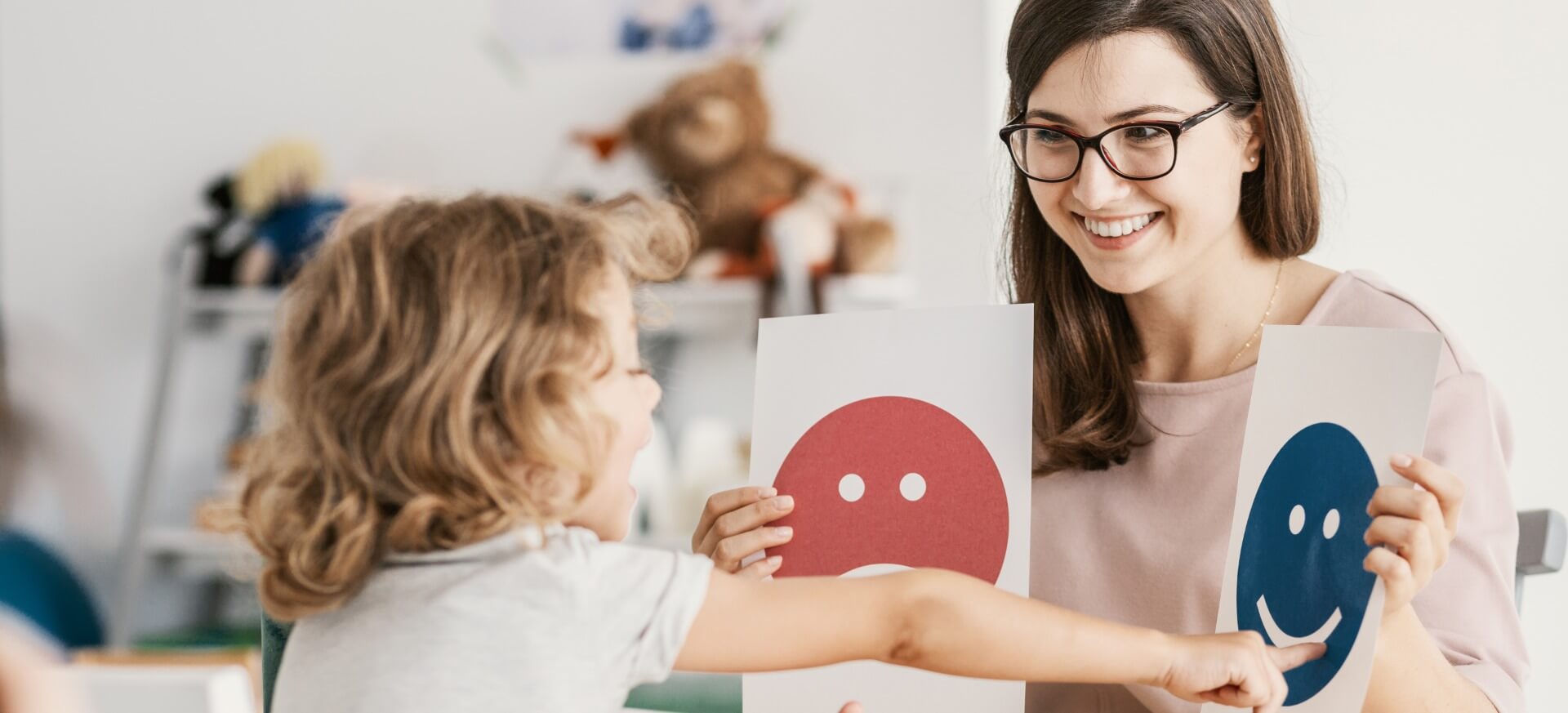 Pädagogin unterrichtet Kleinkind in der Erkennung von Emotionen